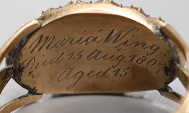A George III yellow metal, seed pearl and plaited hair beneath a rock crystal? panel set mourning ring, inscribed, 'Maria Wing, Died 15th August, 1807, aged 15', size N/O, gross 3.7 grams.